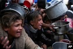 Palestinian girls struggle to reach for food at a distribution center in Khan Younis, Gaza Strip, on Dec. 20, 2024.