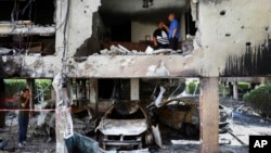 Members of Sror family inspect the damage to their apartment after it was hit by a rocket fired from the Gaza Strip overnight in Petah Tikva, central Israel.