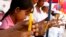 FILE - A Cambodian girl, left, HIV-positive, sits with others who are affected with HIV AIDS hold candles during a vigil in Phnom Penh, Cambodia.