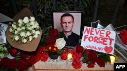 Para pengunjuk rasa meletakkan bunga duka cita di depan bekas gedung kedutaan Rusia di Tbilisi, setelah pengumuman meninggalnya kritikus terkemuka Kremlin, Alexey Navalny di penjara Arktik, 16 Februari 2024. (Vano SHLAMOV / AFP)