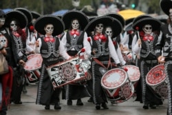 FILE - Performers participate in the Day of the Dead parade in Mexico City.