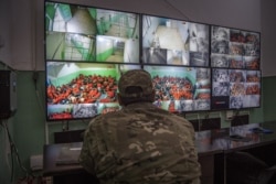 FILE - A fighter with the Syrian Democratic Forces (SDF) monitors on surveillance screens prisoners accused of being affiliated with the Islamic State (IS) group, at a prison in the northeastern Syrian city of Hasakeh, Oct. 26, 2019.