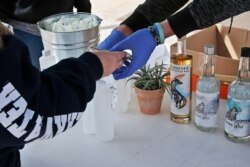 A customer buys two 8 oz. bottles of hand sanitizer at the Prairie Distillery, which has switched from making liquor to making hand sanitizer due to the coronavirus pandemic, in Guthrie, Okla., March 21, 2020.