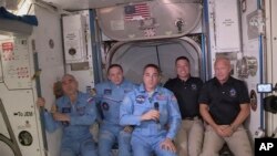 This photo provided by NASA shows Bob Behnken and Doug Hurley, far right, joining the the crew at the International Space Station, after the SpaceX Dragon capsule pulled up to the station and docked May 31, 2020. 