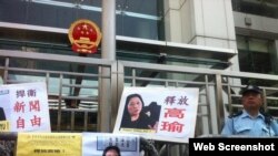 示威者在香港中联办大楼外面放置了要求释放高瑜的标语和图片，旁边是警察（2015年4月17日，网络资料图片）