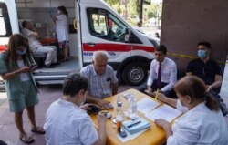 FILE - Iranian citizens prepare to get vaccinated with AstraZeneca vaccine against the coronavirus disease (COVID-19) at a mobile vaccination center in Yerevan, Armenia, July 19, 2021.