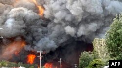 Api dari kebakaran hutan yang tak terkendali terlihat dari daerah perumahan terdekat di Harrington, sekitar 335 kilometer timur laut Sydney, Australia, dalam foto selebaran yang diambil oleh Kelly-ann Oosterbeek. (Foto: AFP)