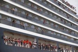 Passengers wave towels as they are about to leave MS Westerdam, a cruise ship that spent two weeks at sea after being turned away by five countries over fears about the coronavirus, as it docks in Sihanoukville, Cambodia Feb. 14, 2020.