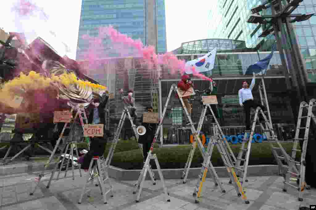 South Korean peace activists on the ladders light smoke bombs during a rally supporting Myanmar&#39;s democracy in Seoul.