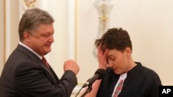 Ukrainian President Petro Poroshenko, left, looks at newly-released Ukrainian pilot Nadiya Savchenko during their meting in the Presidential Office in Kyiv, Ukraine, May 25, 2016.