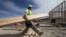 Construction worker Miguel Fonseca carries lumber as he works on a house frame for a new home, Nov. 16, 2012, in Chula Vista, Calif.