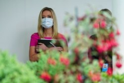 White House Press Secretary Kayleigh McEnany wears a protective face mask as she listens as U.S. President Donald Trump holds a coronavirus disease outbreak press briefing in the Rose Garden of the White House, May 11, 2020.