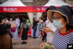 People wearing face masks to protect against the new coronavirus browse merchant tents at a government event aiming to stimulate consumer demand and consumption in Beijing, June 6, 2020.