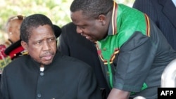 Then-acting President Edgar Lungu (l) talks to foreign affairs minister Harry Kalaba during a military exhibition march, Oct. 24, 2014 to mark Zambia's 50th Independence celebration. 