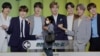 韩国首尔，一名戴着口罩的女子走过一块展示韩国K-Pop组合防弹少年团（BTS）的广告牌（2020年9月30日）。