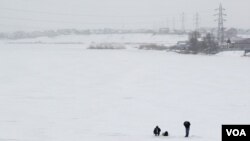 Dua orang memancing di danau yang beku dekat Bucharest, Romania (Foto: dok).