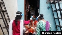 Voluntarios comunitarios de salud controlan la temperatura de una mujer durante una campaña de control de la COVID-19, en un barrio pobre de Mumbai, India, el 16 de agosto de 2020.