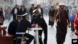 Petugas keamanan mengamati peziarag Budha saat berjalan di Barkhor, sekitar kuil Jokhang di Lhasa, ibukota Tibet, Tiongkok (Foto: dok). Tiongkok terus berupaya untuk menghentikan aksi bakar diri warga Tibet.