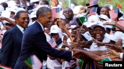 U.S. President Barack Obama and Tanzania's President Jakaya Kikwete (L) greet Tanzanians during an official welcoming ceremony in Dar Es Salaam July 1, 2013. 