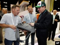 Colorado Gov. Jared Polis, right, looks over a pack made of hemp with Rob Bondurant, left, and Mark Galbraith of Osprey Packs of Cortez, Colorado, in the company's exhibit at the Outdoor Retailer Summer Market in Denver, Colorado, June 19, 2019.