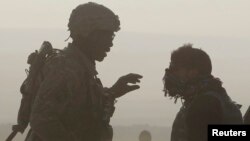 FILE - A U.S. soldier and a translator are silhouetted as they talk to each other at a joint U.S. military and Afghan police checkpoint in Nangarhar province, eastern Afghanistan, March 7, 2012. 