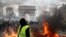 A yellow vest protester walks past a fire on Champs Elysees avenue in Paris, France, March 16, 2019.