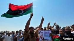 Men hold up a picture of slain lawyer and prominent Libyan activist Abdelsalam al-Mosmary, during his funeral in Benghazi, July 27, 2013.