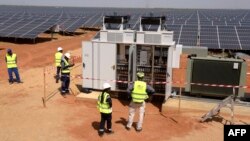 Des techniciens sur un site de production d'énergie photovoltaïque à Bokhol, au Sénégal, le 22 octobre 2016. C’était l’un des plus grands projets d'énergie solaire d'Afrique subsaharienne. (Photo de SEYLLOU / AFP)