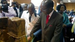 Zimbabwe's President Robert Mugabe cuts his birthday cake as he marks his 93rd birthday at his offices in Harare, Tuesday, Feb. 21, 2017. Mugabe described his wife Grace, an increasingly political figure, as "fireworks" in an interview marking his 93rd bi