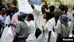 FILE - Zimbabwean riot policemen stand in front of doctors and nurses who are demonstrating over the deteriorating health system, outside Parirenyatwa group of hospitals in Harare, Nov. 18, 2008.