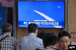 People watch a television screen showing a news broadcast with file footage of a North Korean missile test, at a railway station in Seoul on September 13, 2023.