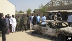 Bystanders gather around a burned car outside the Victory Baptist Church in Maiduguri, Nigeria, Saturday, Dec. 25, 2010