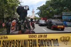 Policías armados resguardan una calle cerrada luego de una explosión afuera de la Catedral del Sagrado Corazón de Jesús, en Makassar, Provincia de Sulawesi del Sur, Indonesia, el domingo 28 de marzo de 2021.