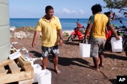 FILE - In this Oct. 13, 2011, file photo, residents collect their morning ration of fresh water made from desalinated sea water in Funafuti, Tuvalu while the atolls are suffering a severe drought and water shortage.