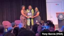 Las sobrinas de Celia Cruz, Celia Cody (izq) y Linda Pritchett (c) reciben las monedas de 25 ctv con la imagen de su famosa tía, durante la celebración a la "Reina de la Salsa" en el Museo Nacional de Historia Estadounidense, el 20 de septiembre de 2024, en Washington.