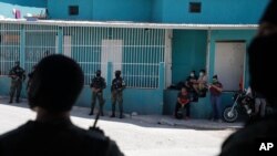 Hondureños usando mascarillas observan cómo soldados y policías acordonan un barrio en el que se detectaron varios casos de coronavirus, durante los días más severos del confinamiento que ya comienza a relajarse.