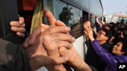 South Koreans hold their North Korean relative's hands on a bus after the Separated Family Reunion Meeting at Diamond Mountain in North Korea, Feb. 25, 2014