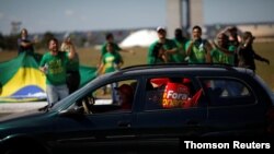 Manifestantes en una caravana de automóviles protestan contra el presidente de Brasil, Jair Bolsonaro, mientras partidarios de Bolsonaro protestan al fondo frente al Congreso Nacional. Brasilia, junio 13 de 2020.
