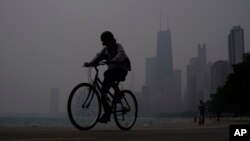 Un ciclista avanza por la ribera del lago Michigan en Chicago bajo una bruma causada por los incendios forestales en Canadá el 27 de junio de 2023.