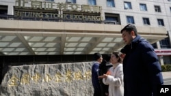 FILE - People walk by the Beijing Stock Exchange in the financial district of Beijing, Wednesday, March 6, 2024. 