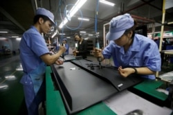 Employees work on the production line of a television factory under Zhaochi Group in Shenzhen, China, Aug. 8, 2019.