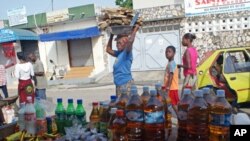 A woman carrying a load on her head walks past Palmeraie Market in Abidjan, April 14, 2011