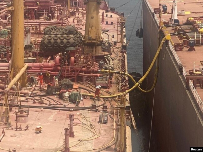 Technicians work on the deck of the replacement vessel as the transfer of oil from the decaying FSO Safer oil tanker began off Yemen July 25, 2023. (United Nations/David Gressly/Handout via REUTERS)