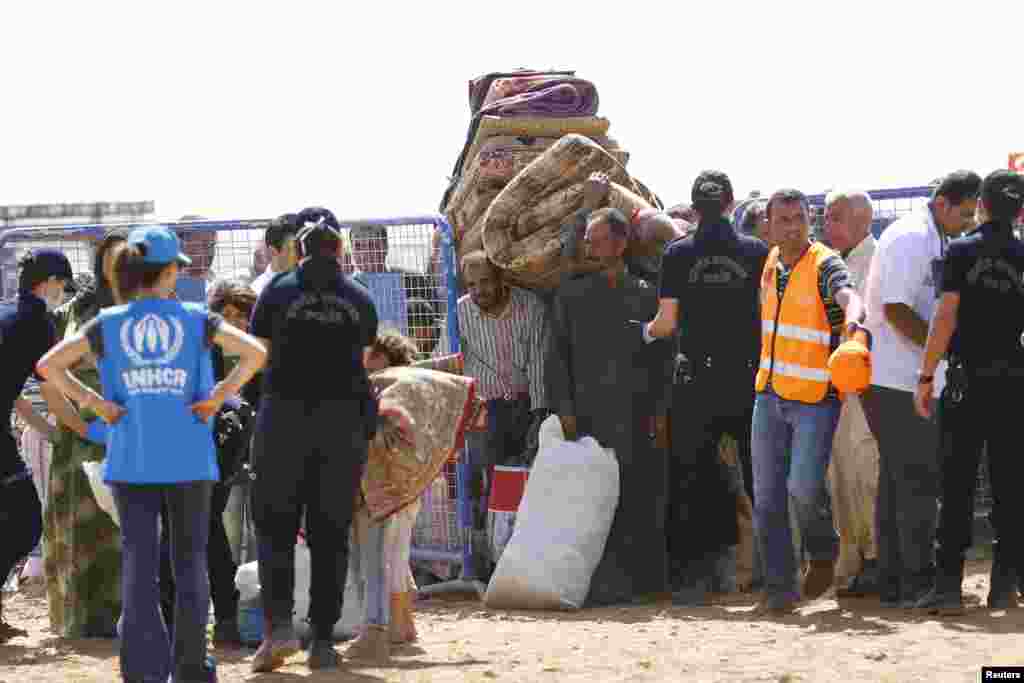 Kurdish Syrian refugees carry their belongings after crossing the Turkish-Syrian border near the southeastern town of Suruc in Sanliurfa province, Sept. 25, 2014.