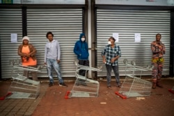 Residents of Yeoville neighborhood of Johannesburg, South Africa, wait in line to enter a grocery store, April 3, 2020.