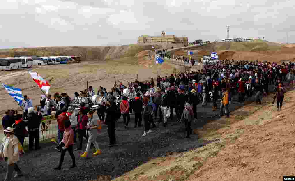 People march towards the Jordan River to participate in a baptism ceremony, near Jericho, in the Israeli-occupied West Bank.