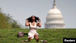 With the U.S. Capitol in the background, Kellye Sims flips her hair up as she basks in the sun, at the National Mall, during a record-setting heat wave in Washington, D.C., U.S., May 3, 2018. REUTERS/Kevin Lamarque TPX IMAGES OF THE DAY - RC147EA5A330