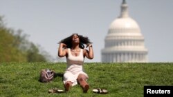 With the U.S. Capitol in the background, Kellye Sims flips her hair up as she basks in the sun, at the National Mall, during a record-setting heat wave in Washington, D.C., U.S., May 3, 2018. REUTERS/Kevin Lamarque TPX IMAGES OF THE DAY - RC147EA5A330