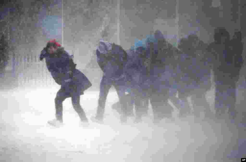 Warga kesulitan berjalan di tengah terpaan angin kencang dan badai salju di kota Boston, Massachusetts.