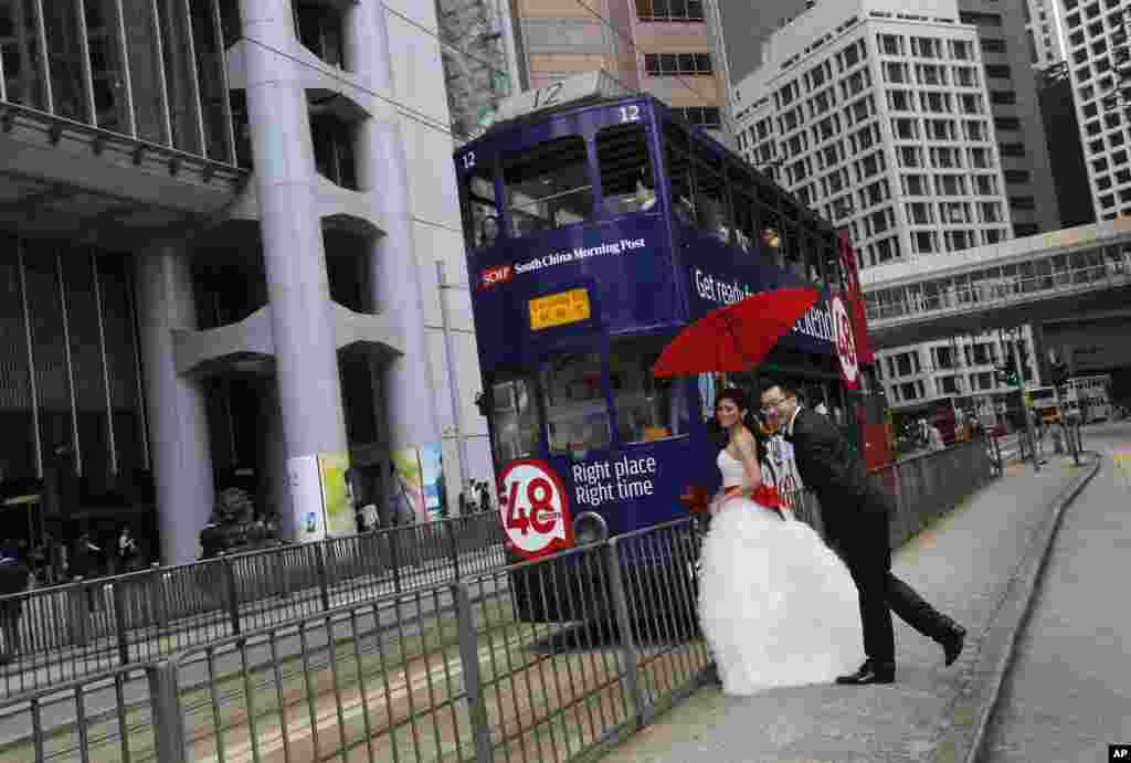 A couple poses for their wedding pictures next to a tram in downtown Hong Kong.